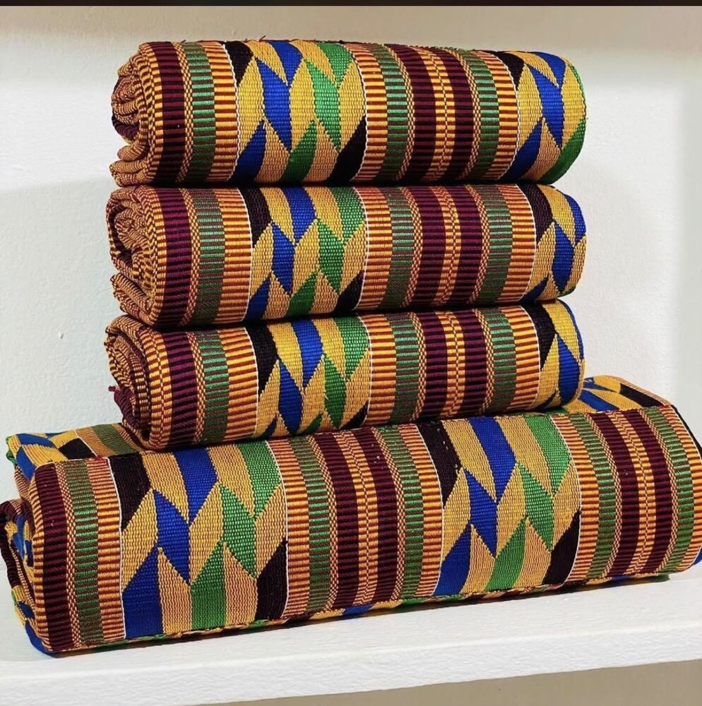 Rolls of green and gold kente cloth on a market shelf